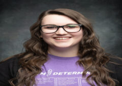 Headshot of Gracie, smiling, wearing glasses and a purple I'm Determined t-shirt.