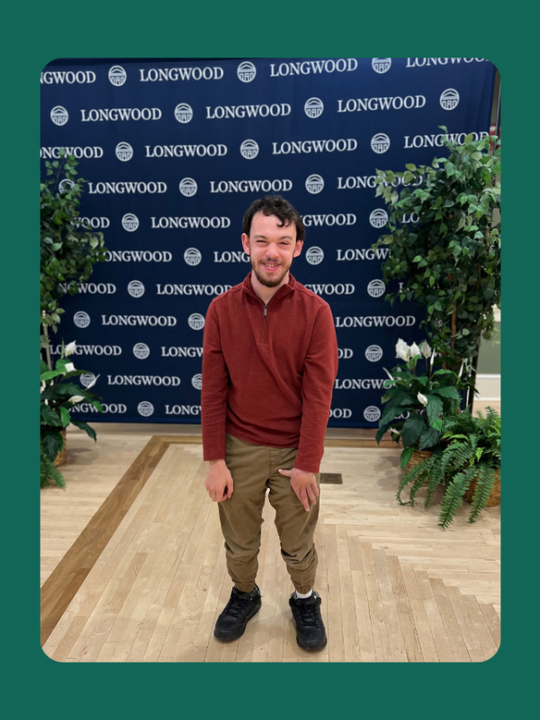 Joseph Jones standing infront of a Longwood University banner.